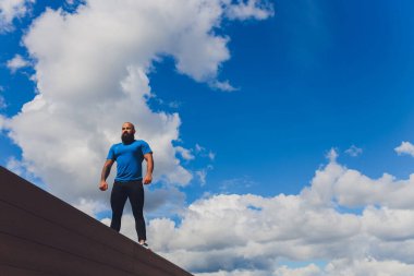 Genç sporcu dışarıda hızlı koşuyor. Spor kıyafetleri giyip, geniş adımlar atarak, sağlıklı bir yaşam biçimi sergileyerek, geniş açılı çekim yaparak..