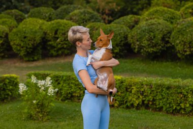 Kollarında bir köpek tutan çekici genç bir kadın..
