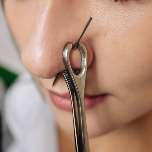 Close-up van een jonge vrouwen gezicht met piercing opknoping uit haar neus. — Stockfoto