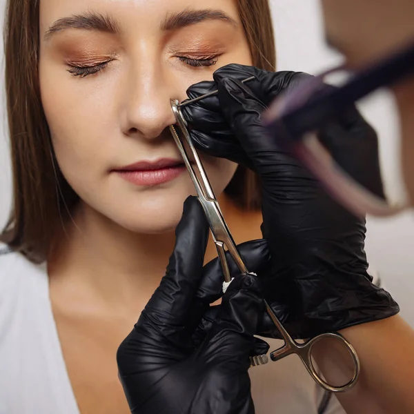 Närbild av en ung kvinnas ansikte med piercing hängande från näsan. — Stockfoto