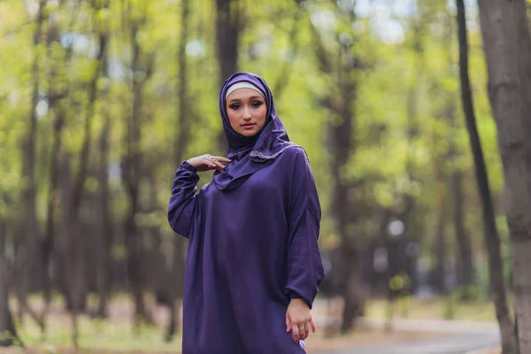 Islamische schöne Frau in einem muslimischen Kleid steht auf einem Sommer Park Straße Hintergrund Wald Herbst Bäume. Welt Hijab Tag. — Stockfoto