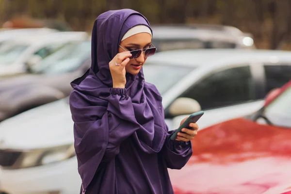 Islamische schöne Frau in einem muslimischen Kleid steht auf einem Sommer Park Straße Hintergrund Wald Herbst Bäume. Welt Hijab Tag. — Stockfoto