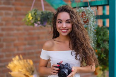 Yaz şehrinde yürürken aynasız kamera kullanan genç ve çekici bir kız öğrenci ya da turist. Kadın fotoğraf çeker ve havanın tadını çıkarır..