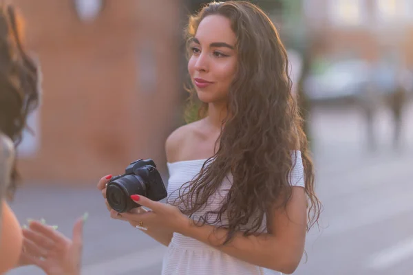 Jonge aantrekkelijke vrouwelijke student of toerist met behulp van een spiegelloze camera tijdens het wandelen in de zomerstad. Vrouw neemt foto 's en geniet van het weer. — Stockfoto