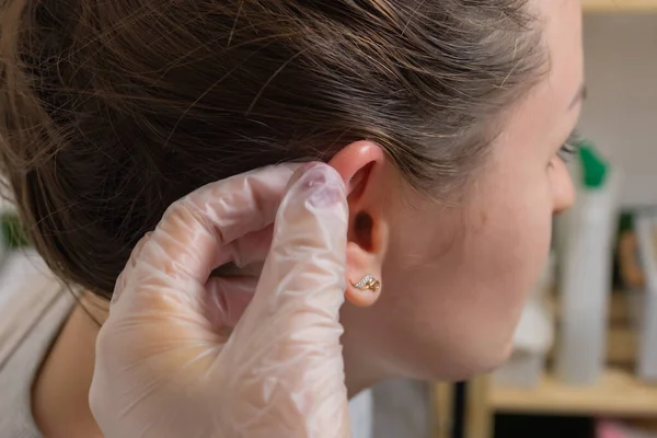 Profissional segurando a jóia de piercing pouco antes de parafusar a bola. — Fotografia de Stock