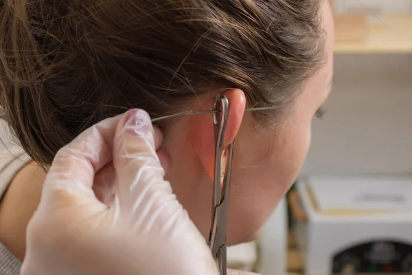 Profissional segurando a jóia de piercing pouco antes de parafusar a bola. — Fotografia de Stock