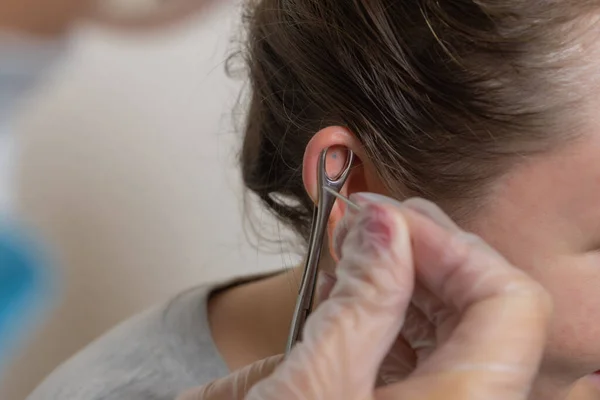 Profissional segurando a jóia de piercing pouco antes de parafusar a bola. — Fotografia de Stock