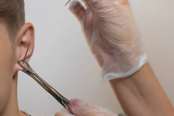 Profissional segurando a jóia de piercing pouco antes de parafusar a bola. — Fotografia de Stock