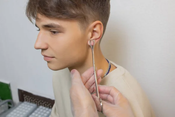 Profissional segurando a jóia de piercing pouco antes de parafusar a bola. — Fotografia de Stock