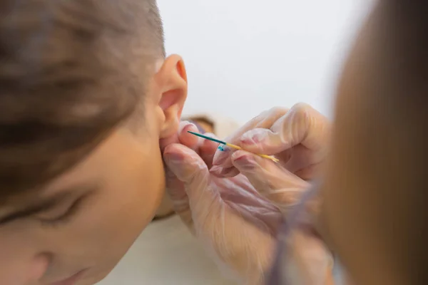 Profissional segurando a jóia de piercing pouco antes de parafusar a bola. — Fotografia de Stock