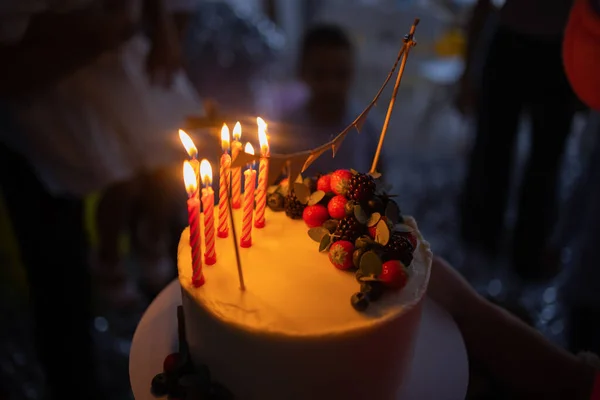 ろうそくの誕生日ケーキ。ケーキの上のろうそく。休日のケーキ。暗い背景にイチゴと美しい白いケーキ。垂直写真. — ストック写真