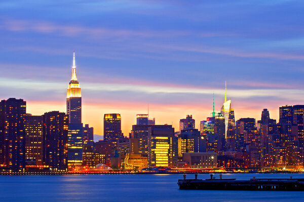 New York City, USA. Downtown buildings in Manhattan with colorful lights, panorama at sunset