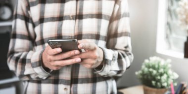 SMS teknolojisi ve sosyal medya ağı konsepti için akıllı telefonu tutan ve kullanan genç bir iş kadını.