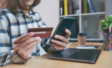 Kredi kartı tutan ve akıllı telefon kullanarak online alışveriş yapan genç bir kadın. uygulama mobil bankacılık teknolojisi kavramı.