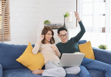 Mutlu Asyalı erkek ve kadın hafta sonunu evde kanepede film izleyerek, gevşeyerek ve patlamış mısır yiyerek geçiriyorlar..