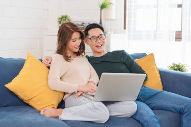 Mutlu Asyalı erkek ve kadın hafta sonunu evde kanepede film izleyerek, rahatlayarak ve eğlenerek geçiriyorlar..