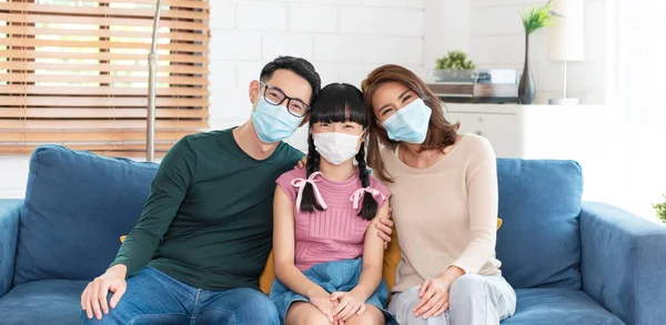 Happy Asian family wearing a mask to protect against viruses at home living room.