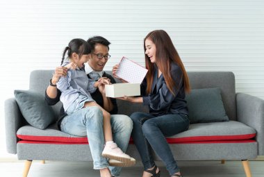 Asian mother and father give present for daughter. concept surprise gift box for happy birthday.	