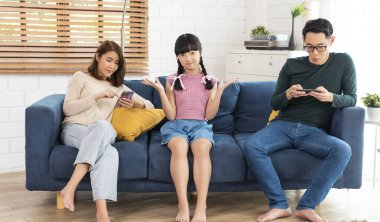 Asian parent using tablet and mobile phones at home. addicted to devices, gadgets dependence overuse.	