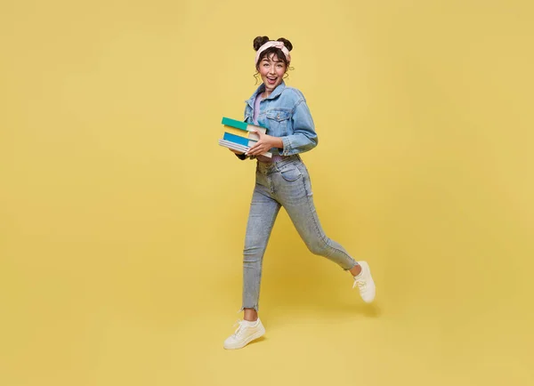 Feliz Chica Asiática Sosteniendo Libro Saltando Sobre Fondo Amarillo Volver — Foto de Stock