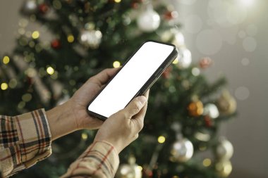 Dijital tatil pazarlama mobil uygulaması tanıtımı ve mevsimsel online bağlantının vurgulanması için Noel ışıklarına karşı yapılan akıllı telefon ekran modeli.