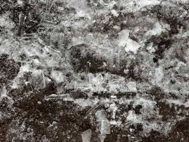 Buzlar eridiği sırada çatıdan düşen buz saçakları ve buz parçacıkları ıslak asfalt kaldırımlara saçılmış. Kopya alanı ile ayrıntılı kış dokusu arkaplanı.