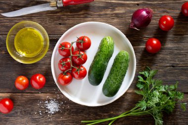 Taze sebzeler, domatesler ve salatalıklar kırsal bir masada.