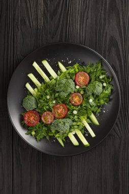 Sebze salatası ve siyah tabakta haute mutfağı. Fotoğraf gösterişsiz.