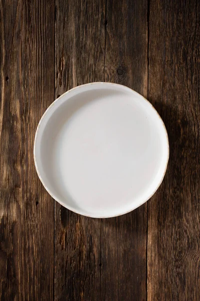 Λευκό άδειο πιάτο σε ξύλινο φόντο, πάνω όψη — Φωτογραφία Αρχείου