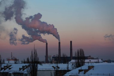 Kış şehrindeki fabrika bacalarından duman çıkıyor.