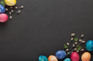 Easter eggs and pussy willow branches on a dark background. top view