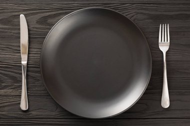 Boş siyah tabak ahşap masa servis eder.