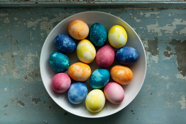 Пасхальные яйца в белом блюде на голубом старом бетонном фоне