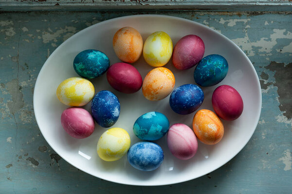 Пасхальные яйца в белом блюде на голубом старом бетонном фоне