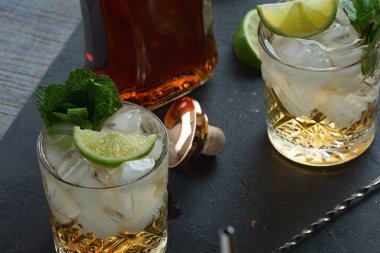 Barın arka planında rom, buz ve naneli alkollü kokteyl.