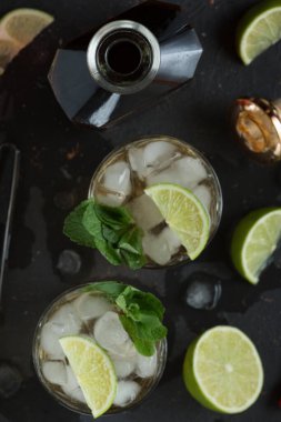 Barın arka planında rom, buz ve naneli alkollü kokteyl.