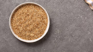 Gri beton arka planda bir kasede susam tohumları.