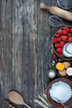 Çerçevesi çilekli turta pişirmek için yapılmış. Tahta masa, üst manzara.