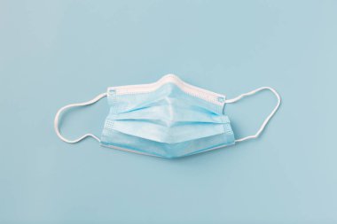 Mavi arka planda tıbbi koruyucu maske. Minimalizm, COVID-19 salgın savunma kavramı