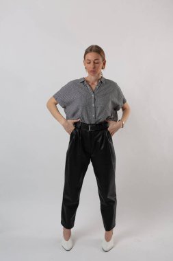 Beyaz bir arka planda poz veren takım elbiseli şık bir kız.