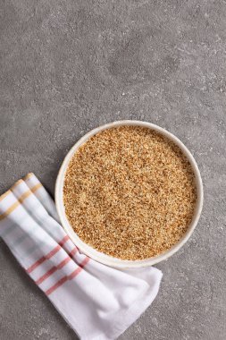 Gri beton arka planda bir kasede susam tohumları.