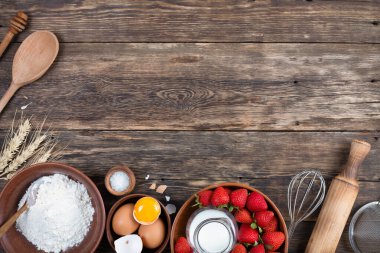 Çerçevesi çilekli turta pişirmek için yapılmış. Tahta masa, üst manzara.