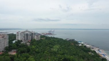 Mavic 2 adlı bir insansız hava aracının plajları ve modern bir şehrin dinlenme alanı ile ilgili 4K görüntüsü.