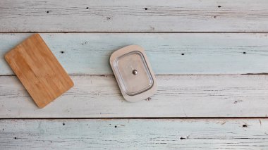 Mutfak tahtası ve tereyağı için boş konteynır kopya alanı olan ahşap masada.