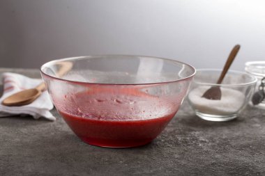 Çilek reçeli yaparken şeffaf bir kasede şekerli rendelenmiş çilek