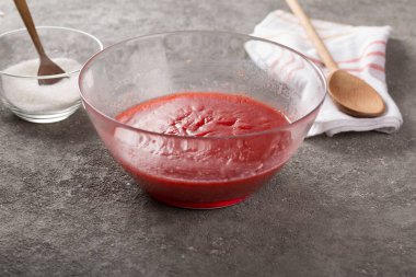 Çilek reçeli yaparken şeffaf bir kasede şekerli rendelenmiş çilek