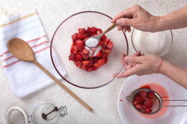 Evinin mutfağında çilek reçeli hazırlayan bir kadın.