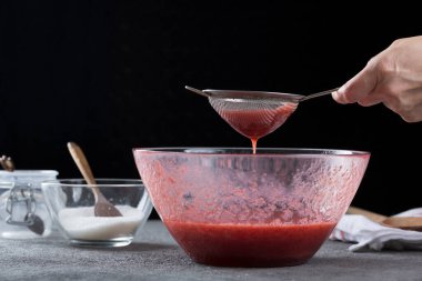 Çilek reçelini süzen kadın, ev yemeği ve yemek pişirme konsepti.