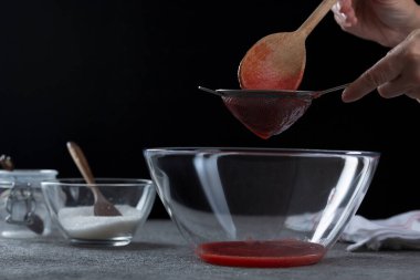 Çilek reçelini süzen kadın, ev yemeği ve yemek pişirme konsepti.