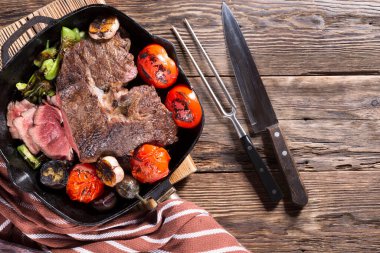 Sebzelerle dolu dökme demir bir tavada kızartılmış bir et parçası, yakın plan.